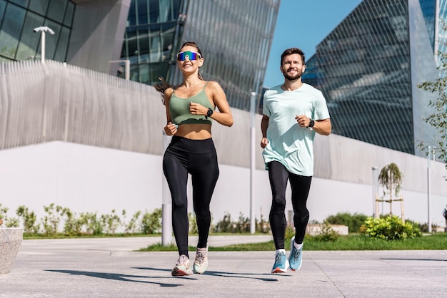 Energetic couple jogging together in an urban setting with striking modern architecture