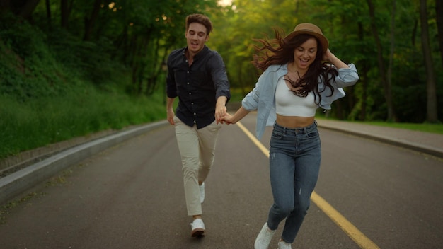 Energetic couple moving fast on road in park Man and woman having fun outdoors