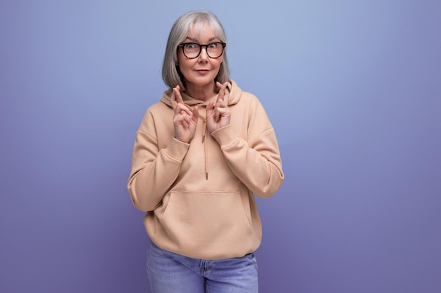 Energetic fashionable mature woman in youth outfit on studio background with copy space