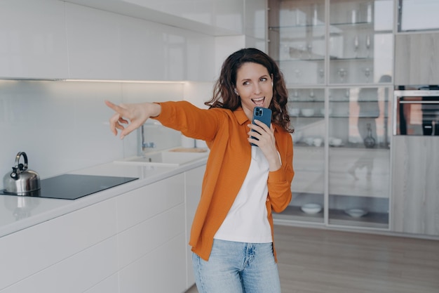 Femmina energica che canta usando il telefono cellulare come microfono divertendosi a praticare la voce a casa