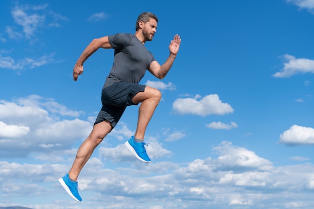 Energetic man athlete sprinter with muscular body run in sportswear outdoor on sky background, motivation.