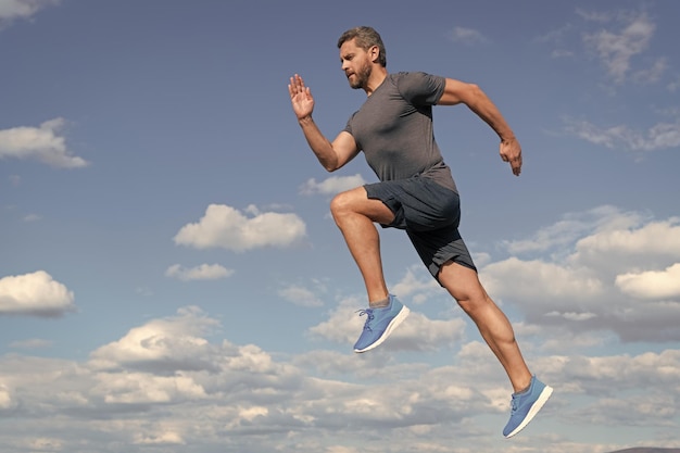 Energetic man athlete with muscular body run in sportswear outdoor on sky background motivation