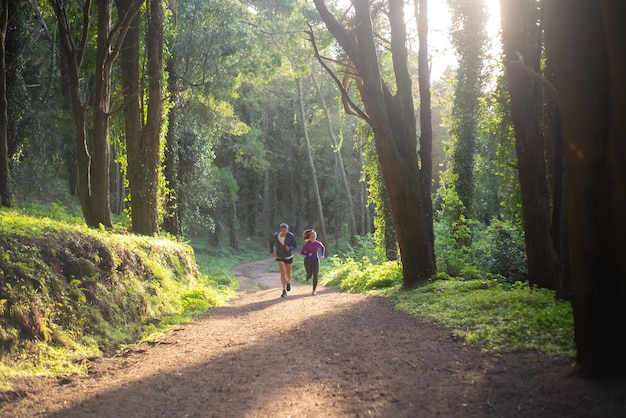 Energetic man and woman jogging in forest. Two sporty people in sportive clothes exercising outdoors. Sport, hobby concept