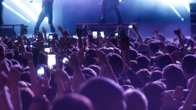 Energetic people dancing with their hands up at the concert