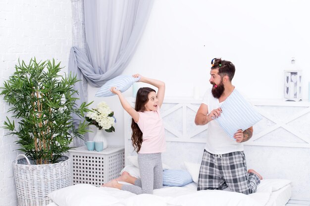 Energetic and positive energetic daughter and father play game\
pillow fight happy family in energetic mood staying energetic till\
deep into night