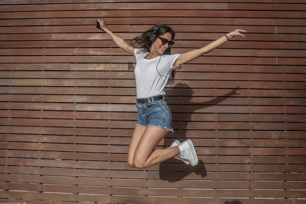 Energetic woman jumping against wall