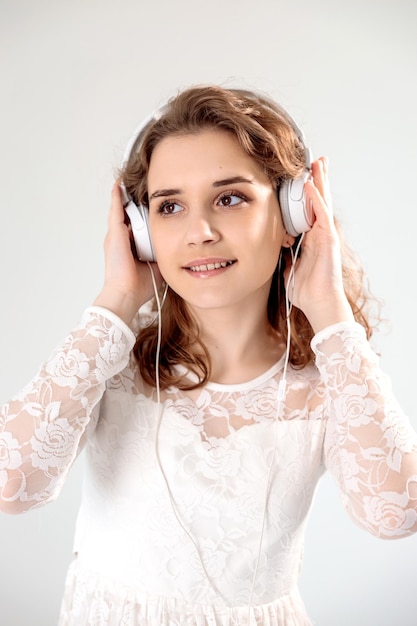 Foto ragazza energica della giovane donna che balla cantando ascoltando la traccia audio del ebook del cantante del podcast di musica nel lettore delle cuffie isolato su priorità bassa bianca