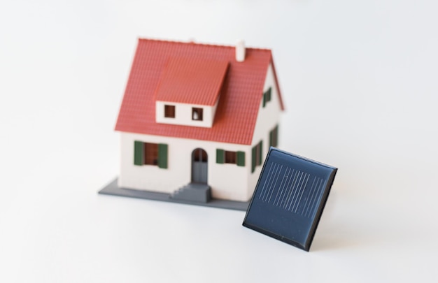 energie, krachtbron, milieu en ecologieconcept - close-up van een levend huismodel en een zonnebatterij of -cel