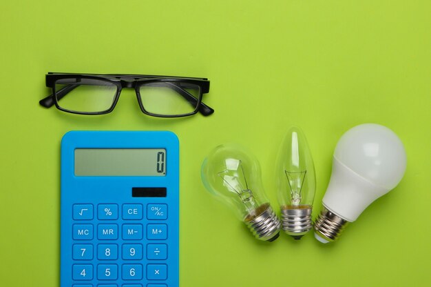 Foto energiebesparend. rekenmachine met gloeilampen, glazen op groen