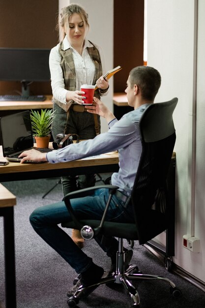 Energiedrank cafeïne. slaaptekort. vermoeidheid uitputting. vrouw die een kopje koffie aanbiedt aan haar collega.