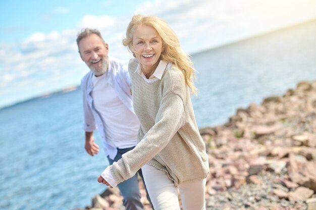 Energieke mooie vrouw en man lopen in de buurt van zee