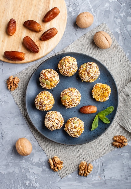 Energy ball cakes with dried apricots, sesame, linen, walnuts and dates on gray 