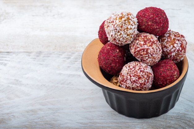 Energy balls in a black glass on a white wooden background. Free space.