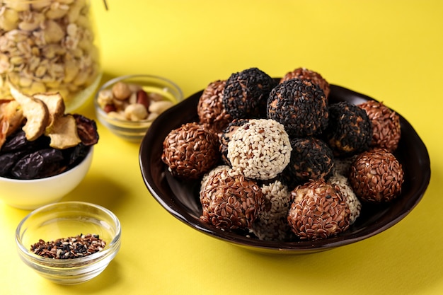 Energy balls and ingredients: nuts, oatmeal and dried fruits on a plate on yellow , 