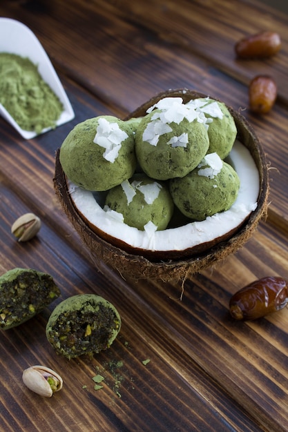 Energy balls with  matcha powder, pistachios, dates  and coconut chips in the half coconut