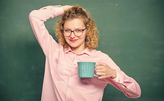 Energy charge for whole day teacher eyeglasses drink coffee\
chalkboard background woman enjoy coffee before classes sip\
recharging body and mind dose of caffeine back to school coffee\
addicted