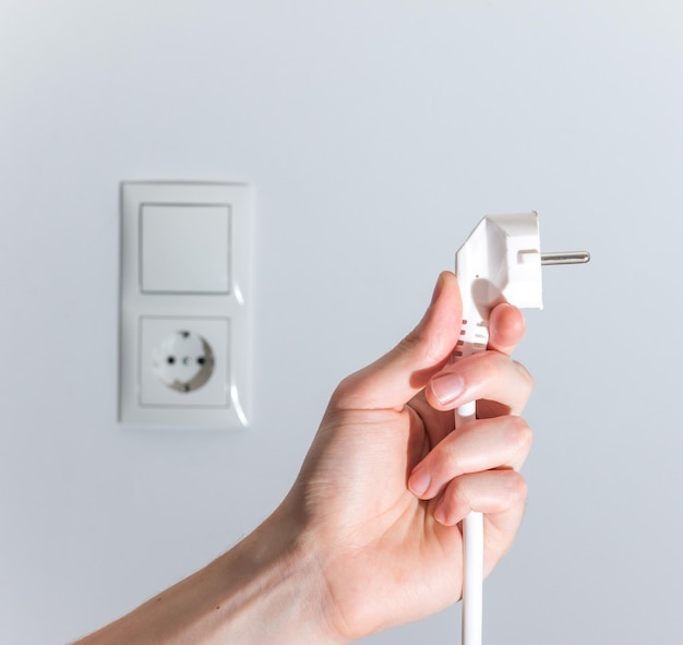 Energy concept Plug ready to connect White cable and plug socket in the blurry background