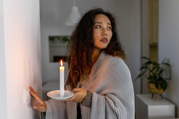 Energy crisis Hand in complete darkness holding a candle trying to turn on light during a power outage Blackout concept