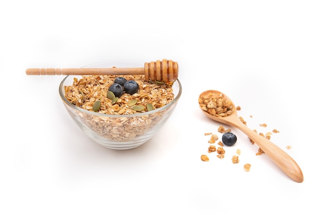 Energy granola on a clear bowl with honey on a white background.