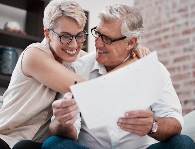 The energy housed in my favourite person Shot of a mature couple going through paperwork on the sofa at home together