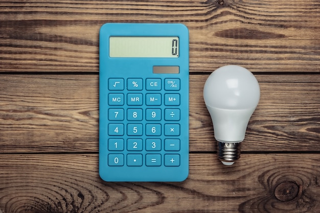 Energy saving concept. Calculator with light bulb on a wooden