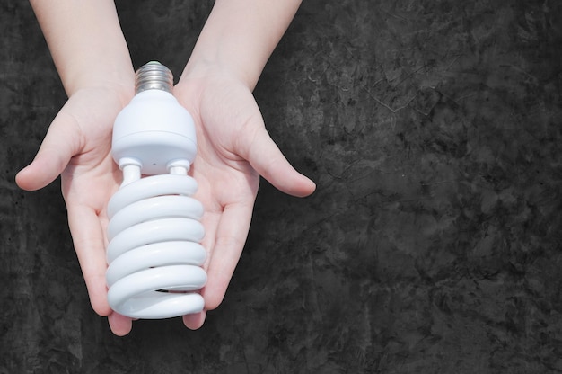 Energy saving concept Woman hand holding light bulb on dark backgroundIdeas light bulb in the hand