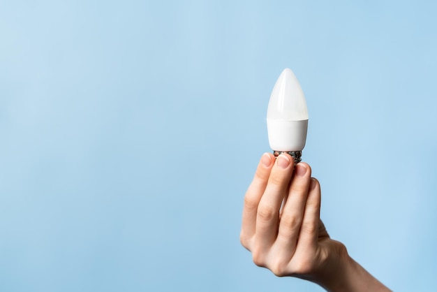 energy saving light bulb in hand on a blue background