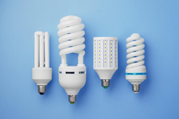 Energy saving light bulbs organized in a row over blue background top view