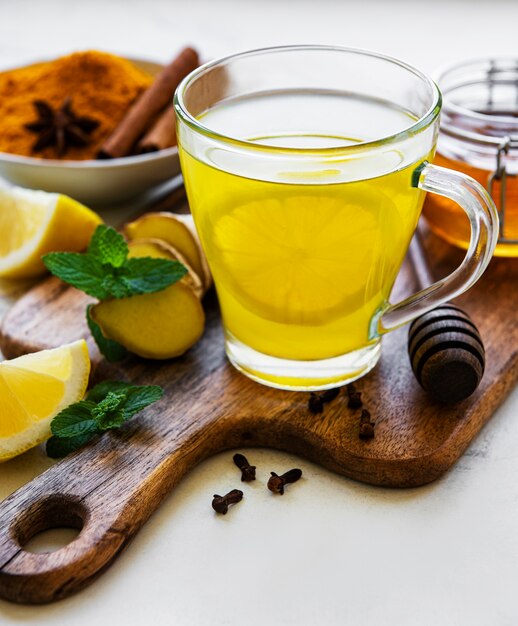 Energy tonic drink with turmeric, ginger, lemon and honey on a white marble background