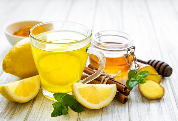 Energy tonic drink with turmeric, ginger, lemon and honey on a white wooden  background