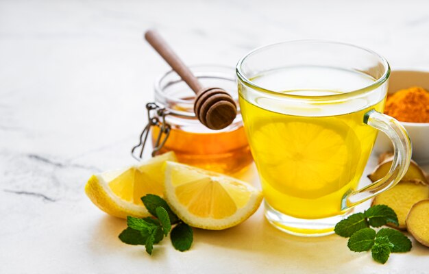 Energy tonic drink with turmeric, ginger, lemon and honey on a white wooden