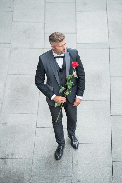 engagement date caucasian tuxedo man celebrates engagement man with rose gift for engagement