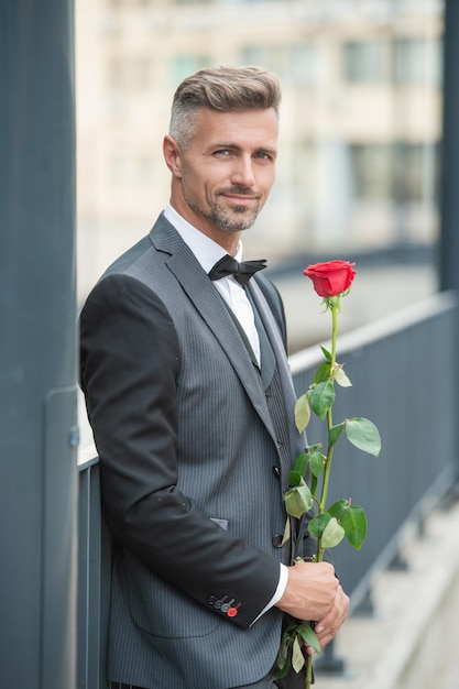 Engagement date cheerful tuxedo man celebrates engagement man with rose gift for engagement