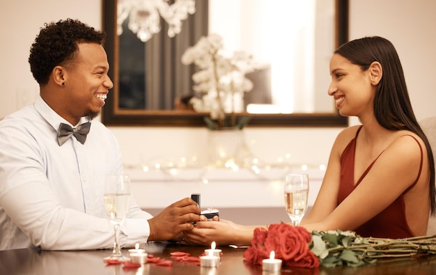 Engagement proposal ring and couple on date at restaurant with roses gift and love celebration Jewellery in young black man hands woman or people together at luxury table with candles and bouquet