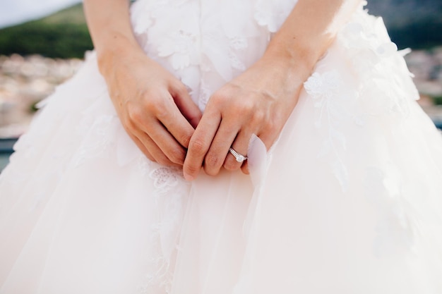 Engagement ring on brides hand with wedding dress close up