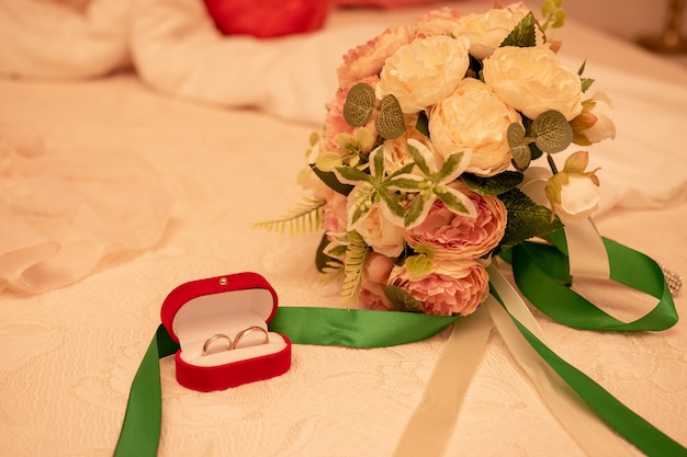 Engagement rings in red box, wedding rings in red box. Engagement rings and the bride's bouquet.