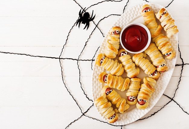 Enge worstmummies in deeg met grappige ogen op lijst. Grappige decoratie. Halloween eten. Bovenaanzicht Plat leggen