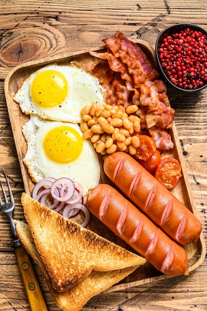 Engels ontbijt in een houten dienblad met gebakken eieren, worstjes, spek, bonen en toast