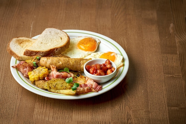 Engels ontbijt met worstjes, roereieren, bonen en toast in een bord op een houten achtergrond