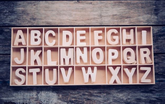 Foto engelse letters worden in alfabetische volgorde in een houten kist geplaatst.