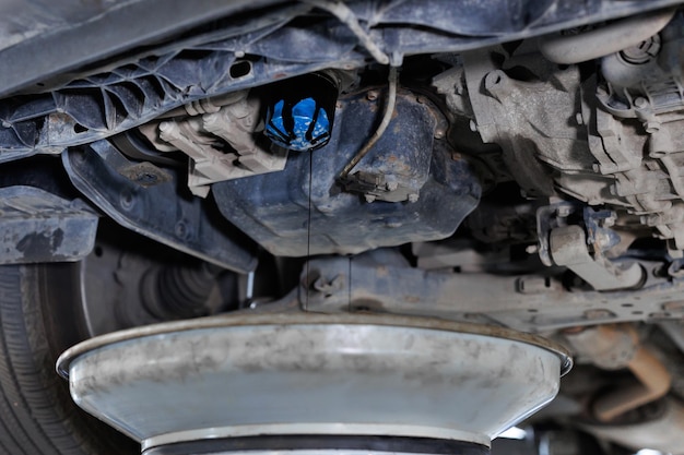 Foto cambiamento dell'olio del motore nel servizio auto auto è su ascensore idraulico in officina garage