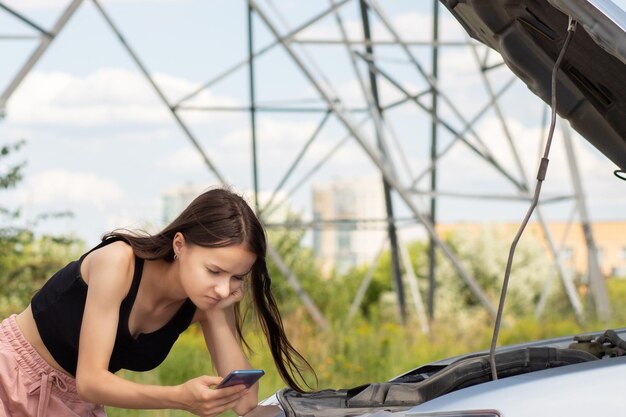 engine problemswoman with a broken auto on the road is upset with an open hoodhelp is called by phone