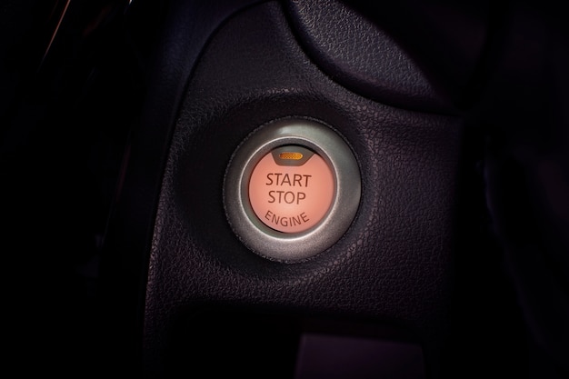 Engine start button of car with a orange light.