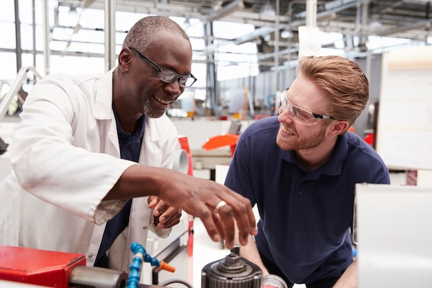 Engineer advising a male apprentice in a factory close up