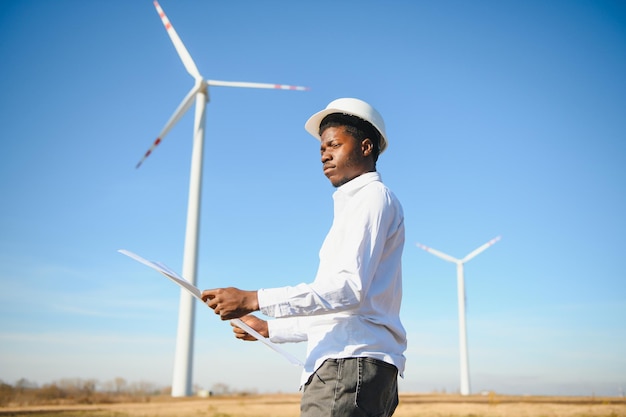 Ingegnere uomo africano in piedi con turbina eolica