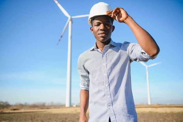 Ingegnere uomo africano in piedi con turbina eolica