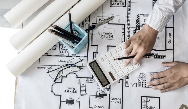 Photo engineer or architect is pressing a calculator to calculate the buildings structure and balance