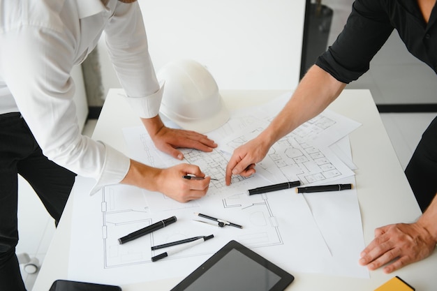 Engineer or architect teamwork working on construction project\
with building model and blueprint in office construction\
concept