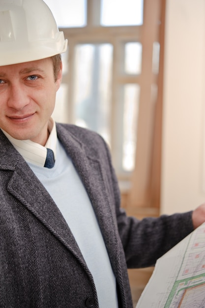 Photo engineer or architect in the white hard hat with the drawings.