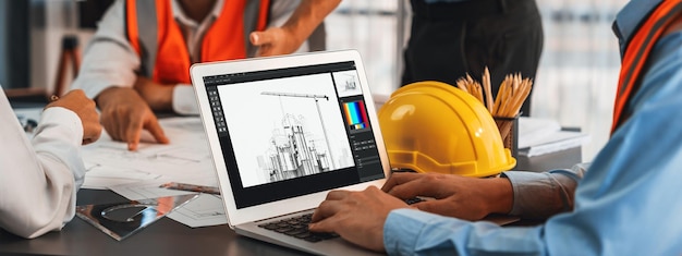 エンジニアと建築家が一緒にブレインストーミングしノートパソコンを使用してブループリントを設計し精密なデジタルインテリアや構造設計のために建築ソフトウェアで作業します Insight
